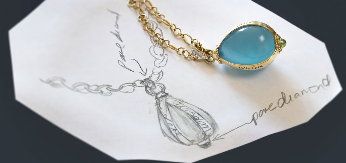 Mary Margrill Bespoke Love, Greace, & Wisdom Pendant with Large Pale Blue Semi Transparant stone held in a gold cage enscribed with the words love, grace, and wisdom, a peridot cabichon accents the bottom. The chain is hand made fancy links, 30 inches long.