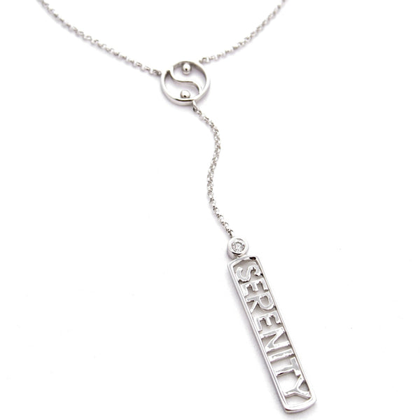 A sterling silver 'Y' necklace featuring a delicate chain with a small circular yin-yang symbol and a dangling rectangular bar with the word 'SERENITY' and a bezel set diamond, shown on a plain white background.